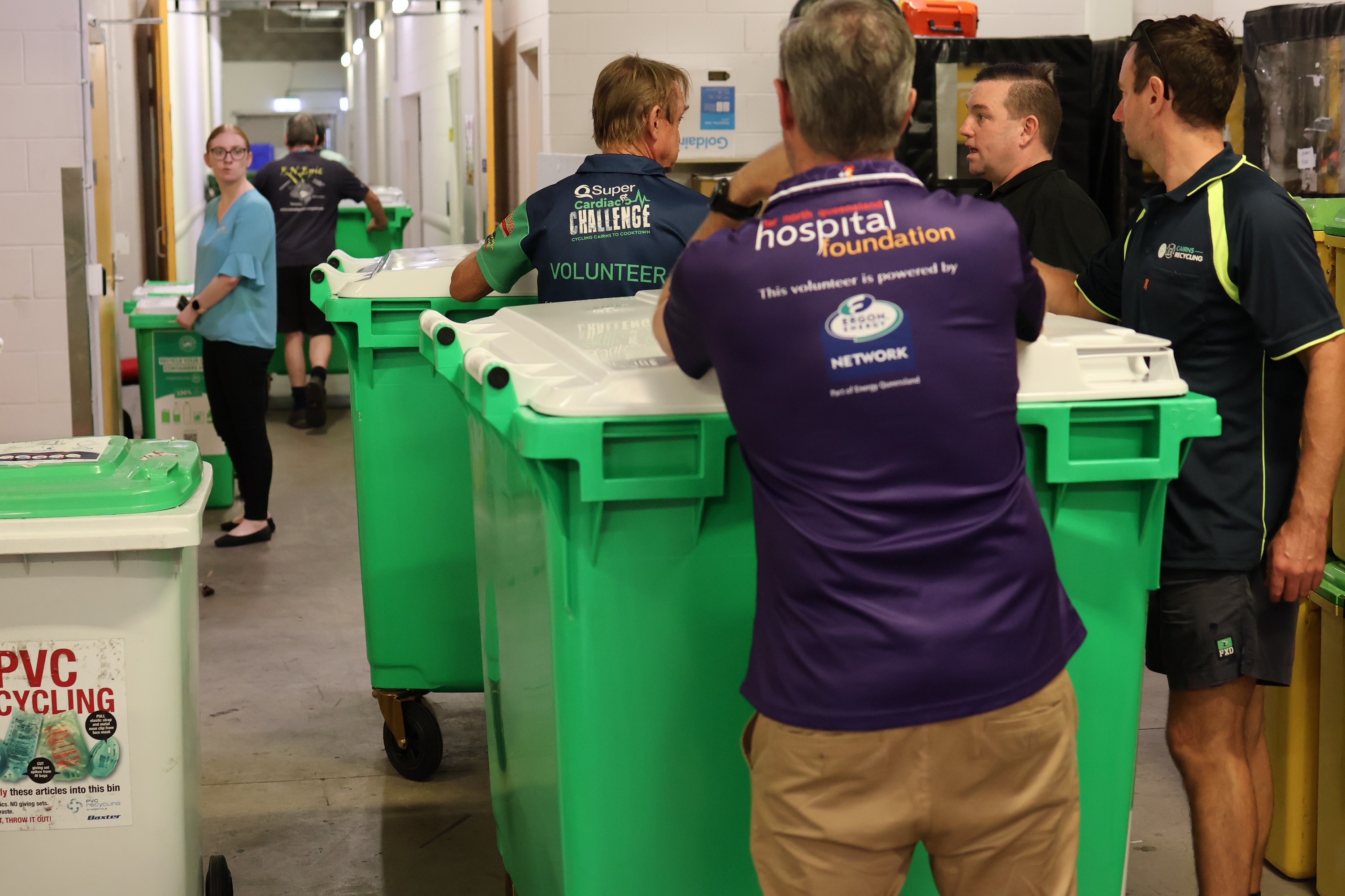 People in hall way leaning on large garbage bin