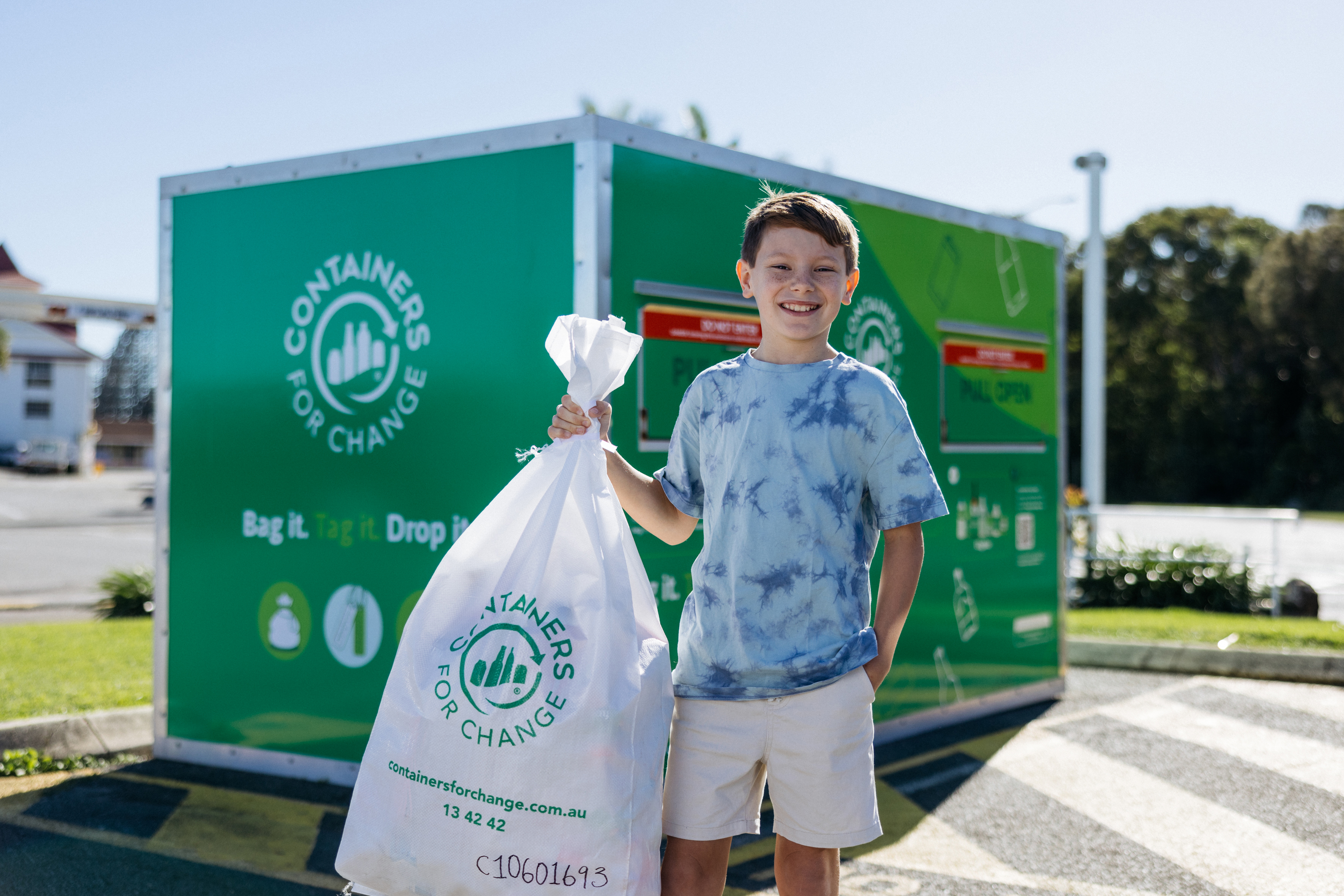 Boy holding bag of conatiners in front of Bag Drop