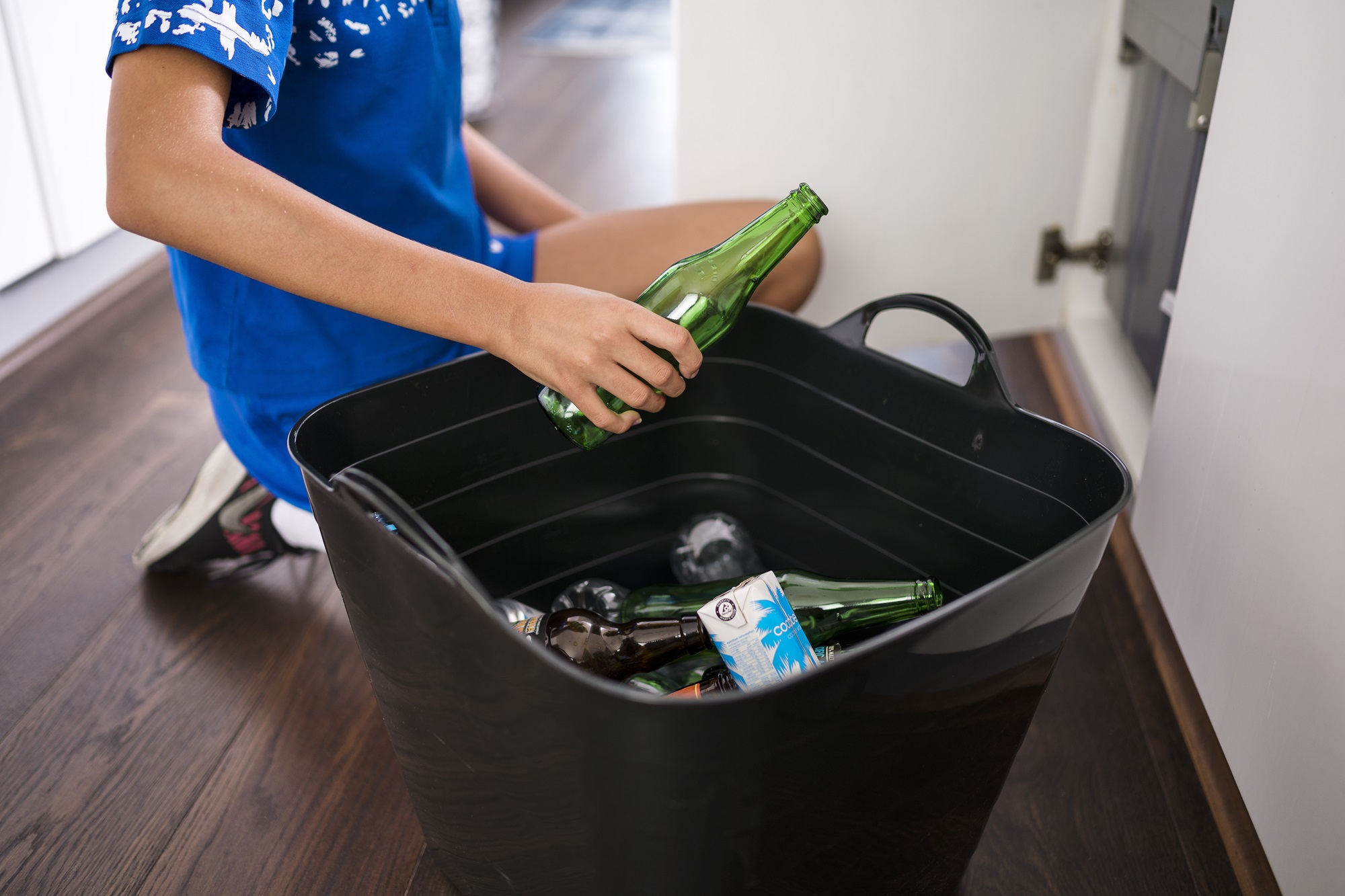 Person holding bottle over black bucket